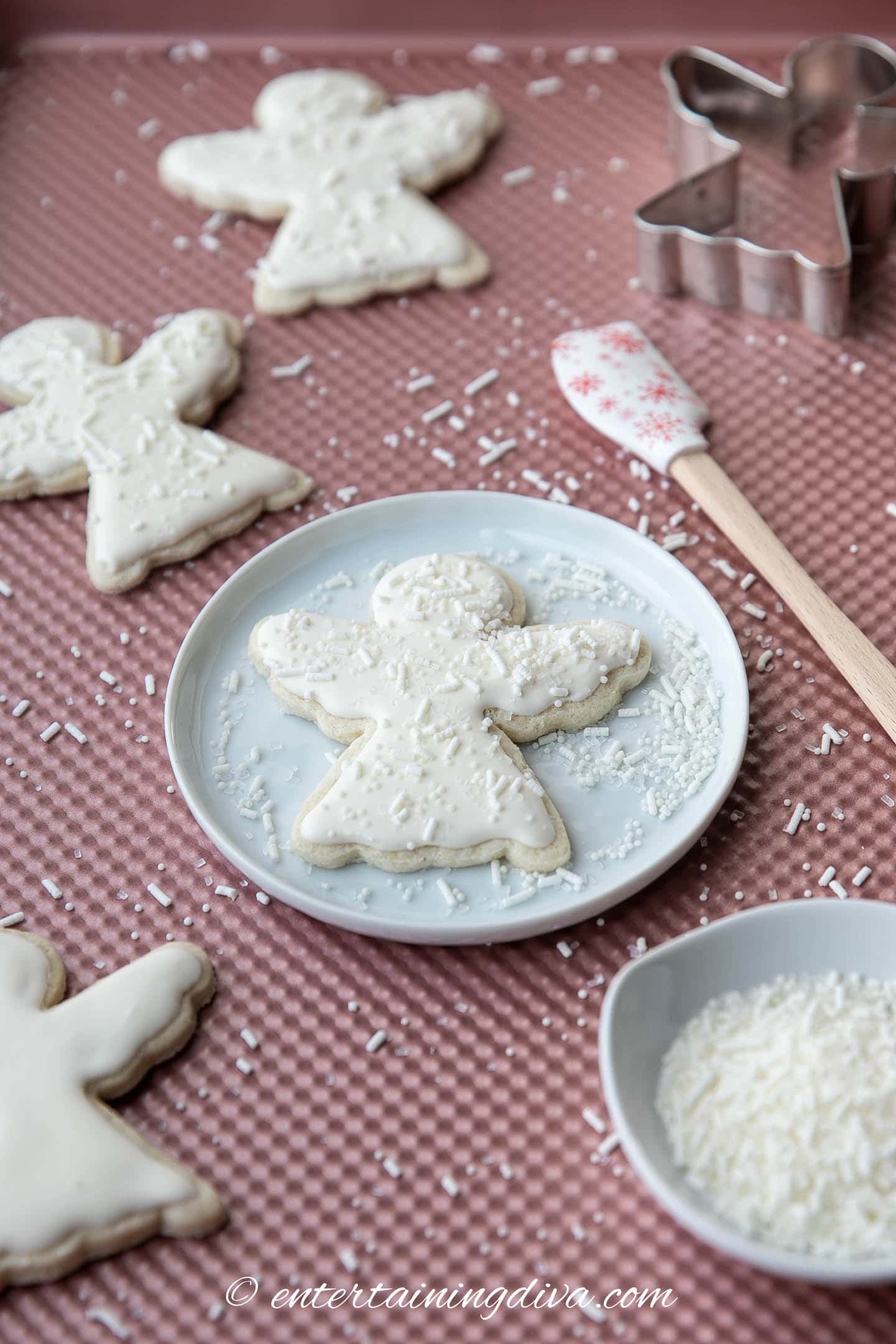 Christmas angel sugar cookies decorated with white royal icing and sprinkles on a plate