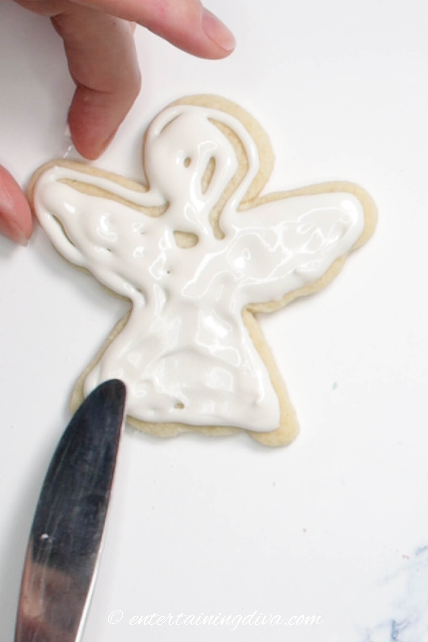 Icing being spread out on the cookie with a knife
