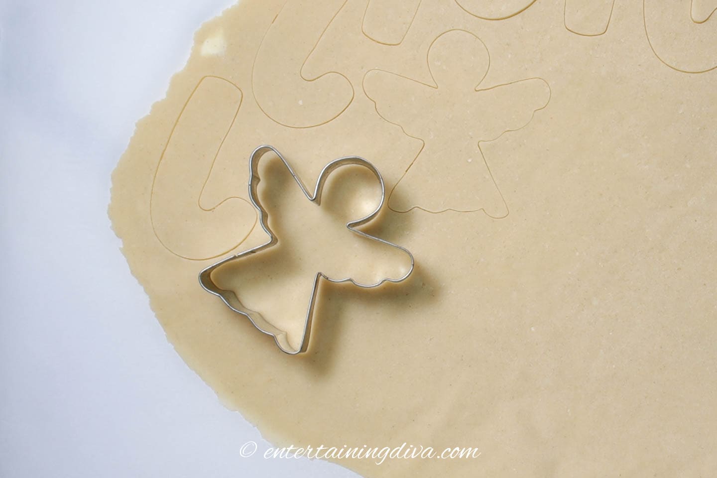 Angel cookie cutter on rolled sugar cookie dough
