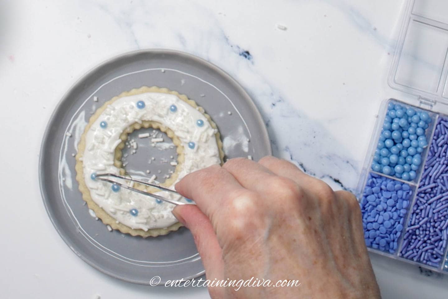 Using tweezers to place sugar balls on the wreath cookies