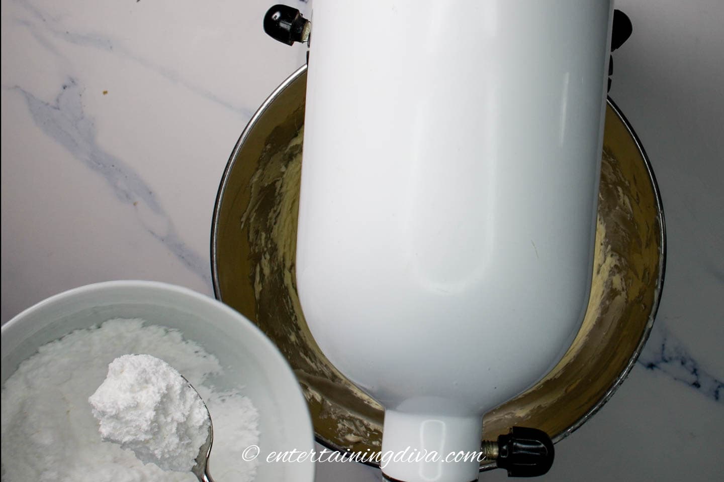 Adding icing sugar to the mixer with a spoon