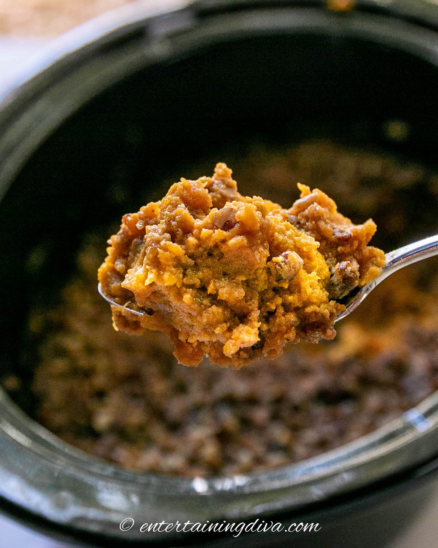 A spoonful of sweet potato casserole above a slow cooker