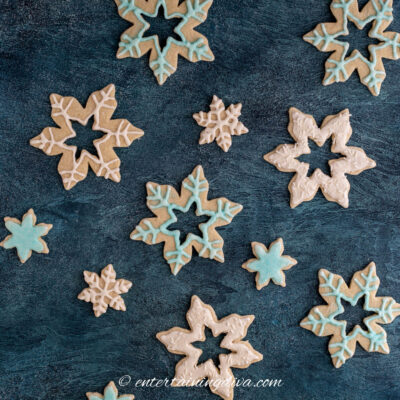 snowflake sugar cookies decorated with white royal icing and blue sprinkles