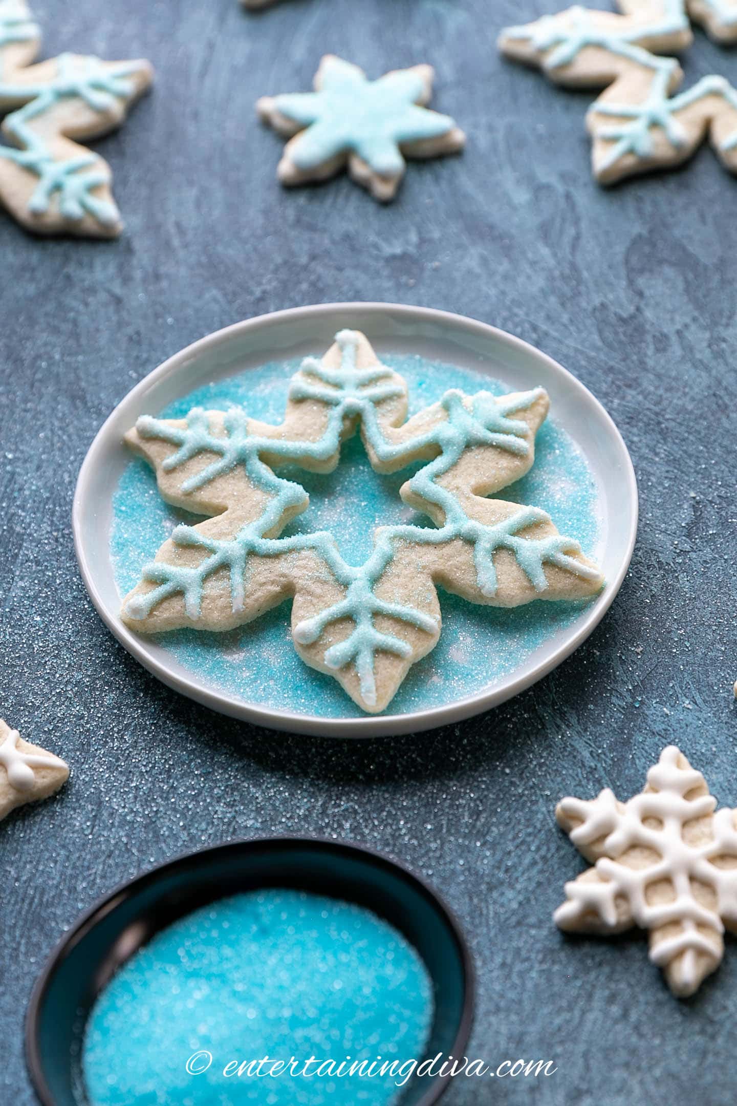 snowflake sugar cookie decorated with lacy white icing design and blue sugar