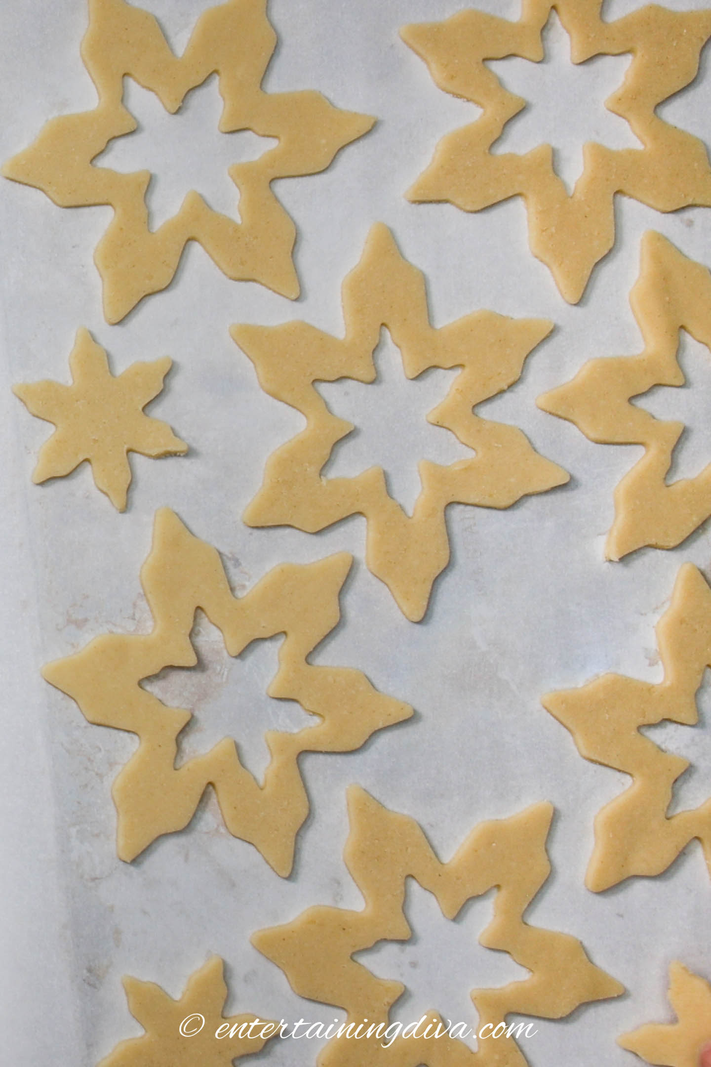 Cut out snowflake sugar cookies on a baking sheet