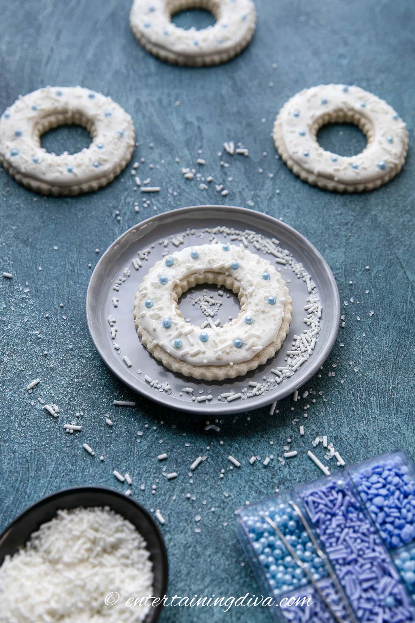 wreath sugar cookies decorated with white royal icing and blue sugar balls