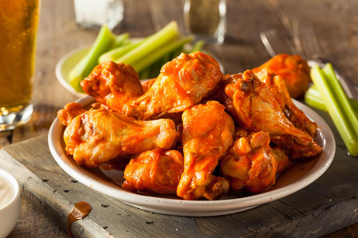 baked buffalo chicken wings on a plate with celery in the background