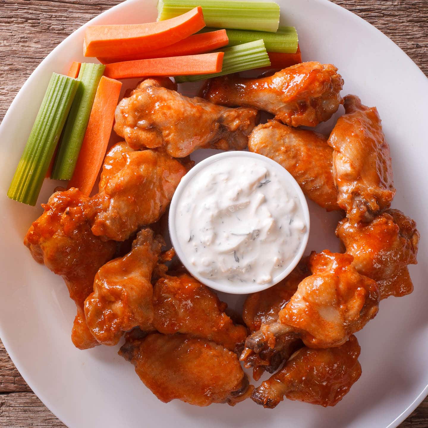 crispy oven baked hot wings on a plate with blue cheese sauce, celery and carrots