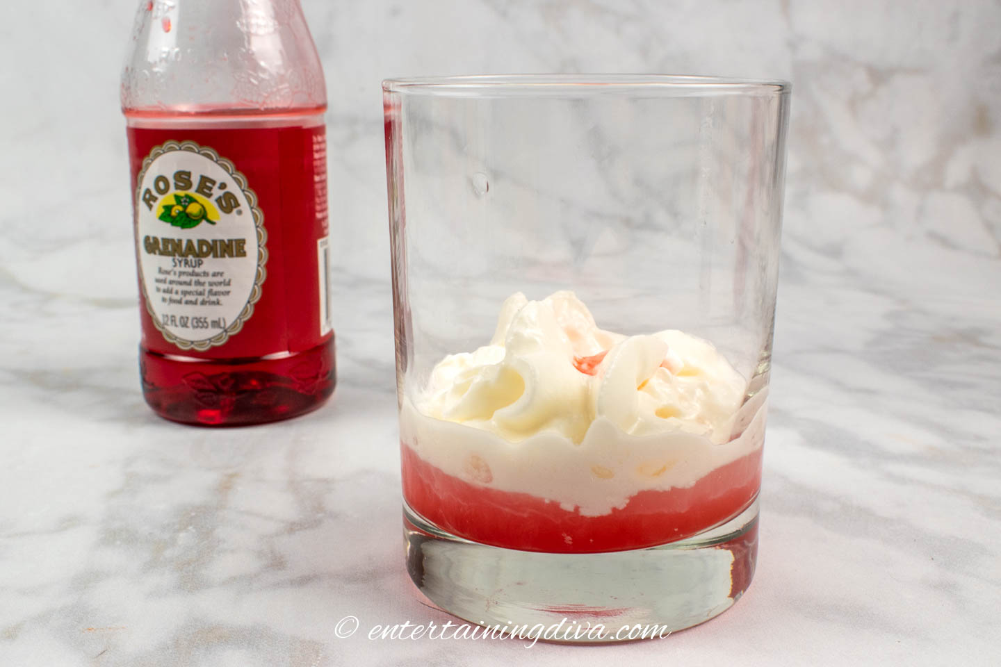 grenadine, vodka and whipped cream in a glass