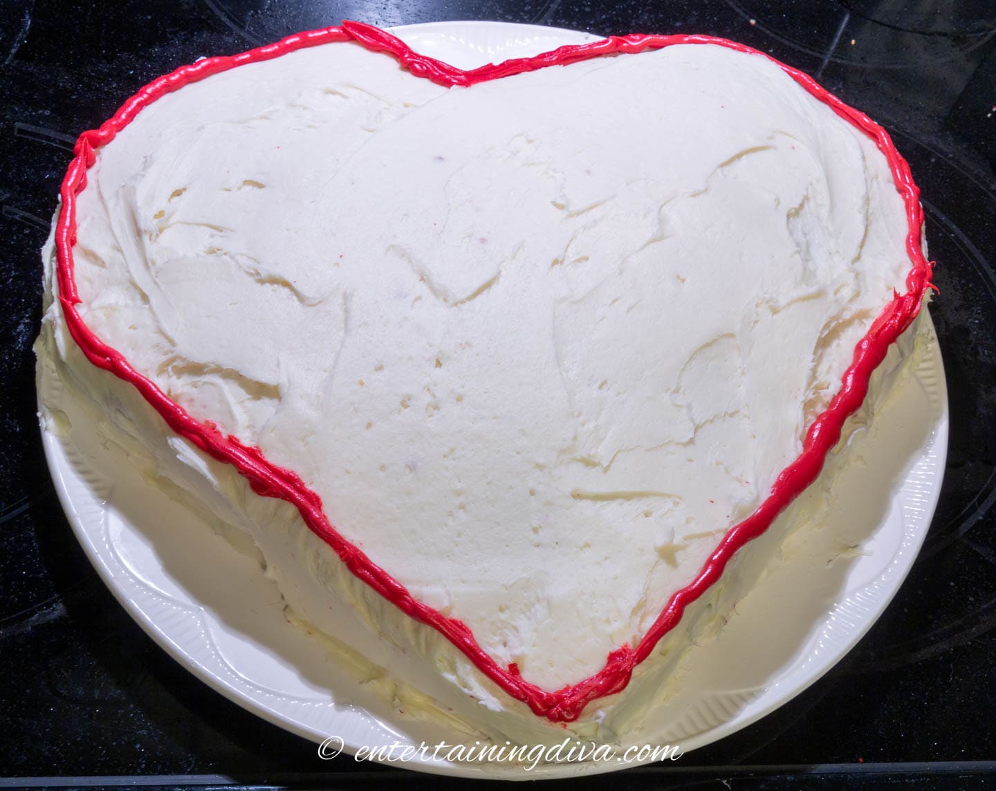 white heart cake outlined with red icing