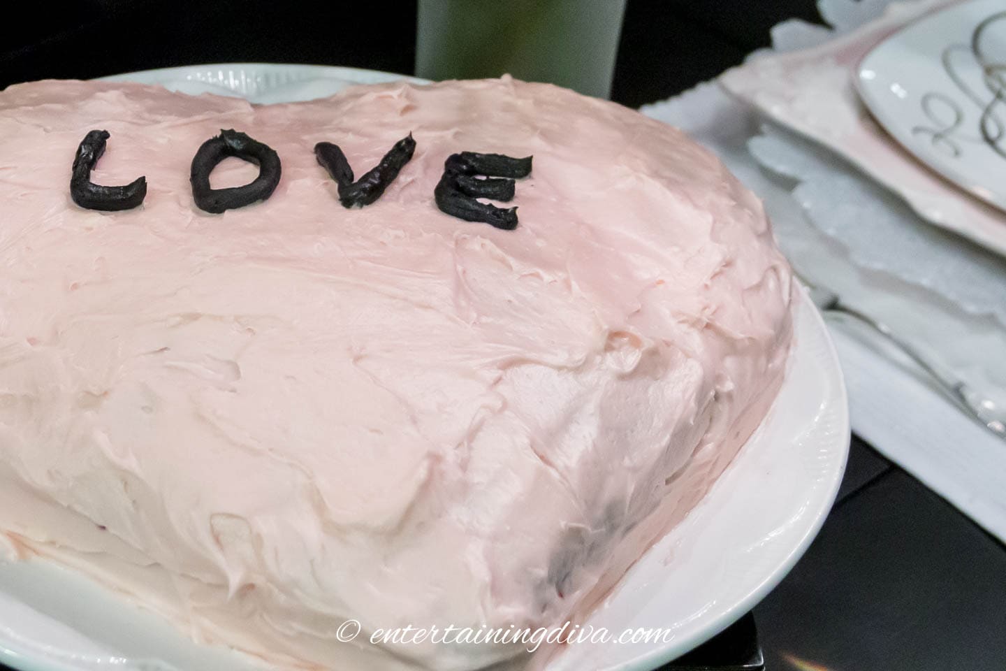 heart cake with pink frosting and the word LOVE on the top