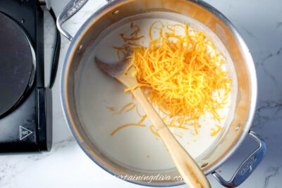 grated cheese being added to the milk and stock mixture