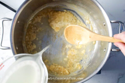 chicken stock being added to onion mixture in pot