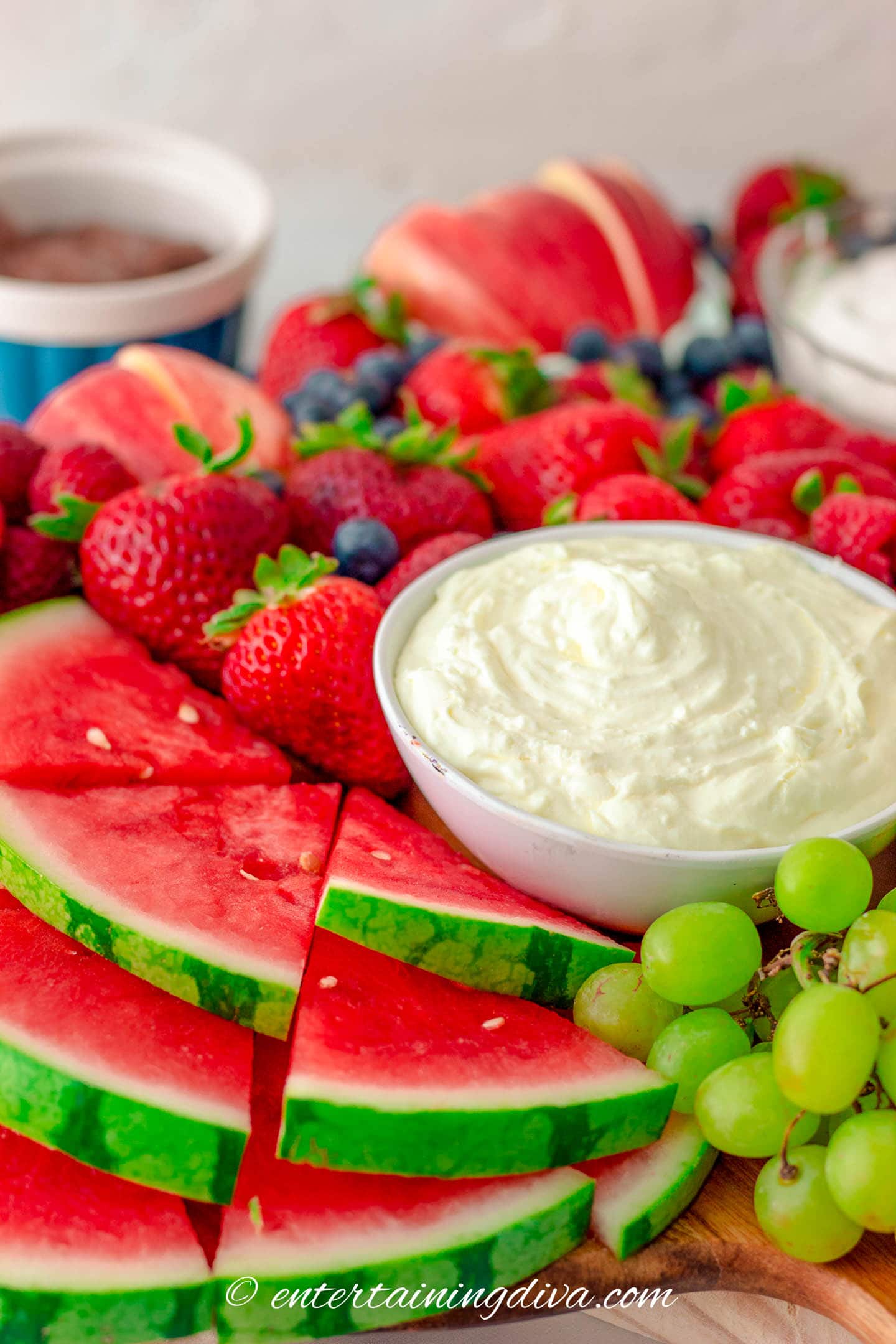 Close up of a fresh fruit charcuterie board with cream cheese fruit dip in a bowl