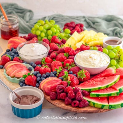 fruit charcuterie board with green grapes, strawberries, raspberries, blueberries, watermelon, pineapple and dips