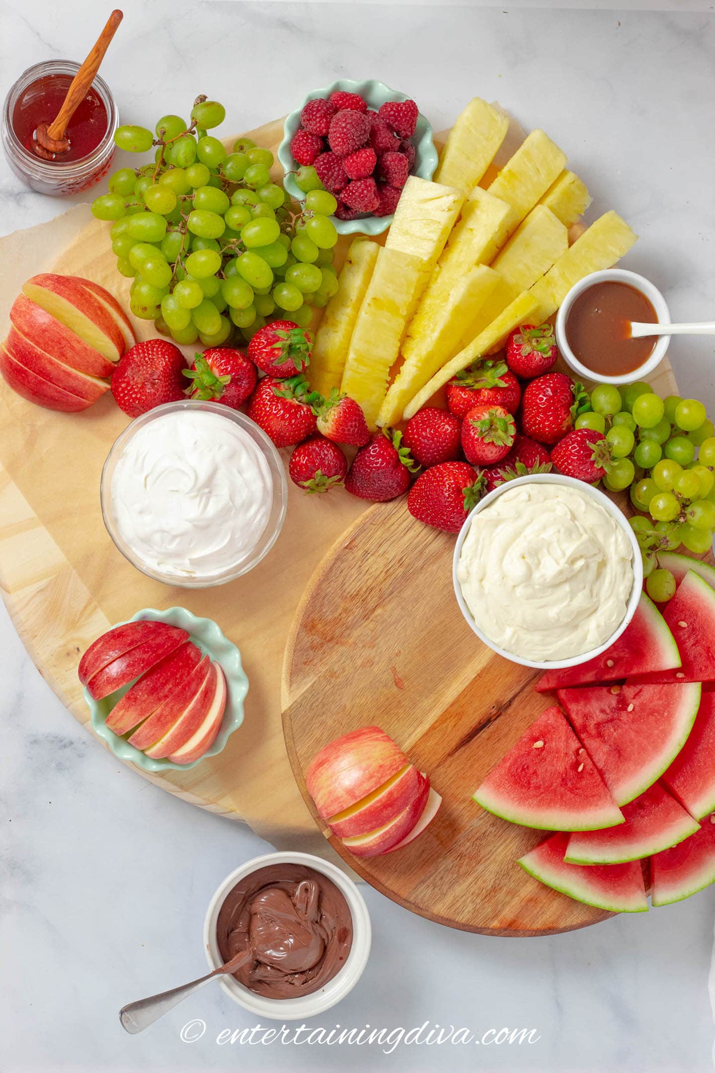 fruit charcuterie board with strawberries, apples, pineapple, watermelon, grapes and dips