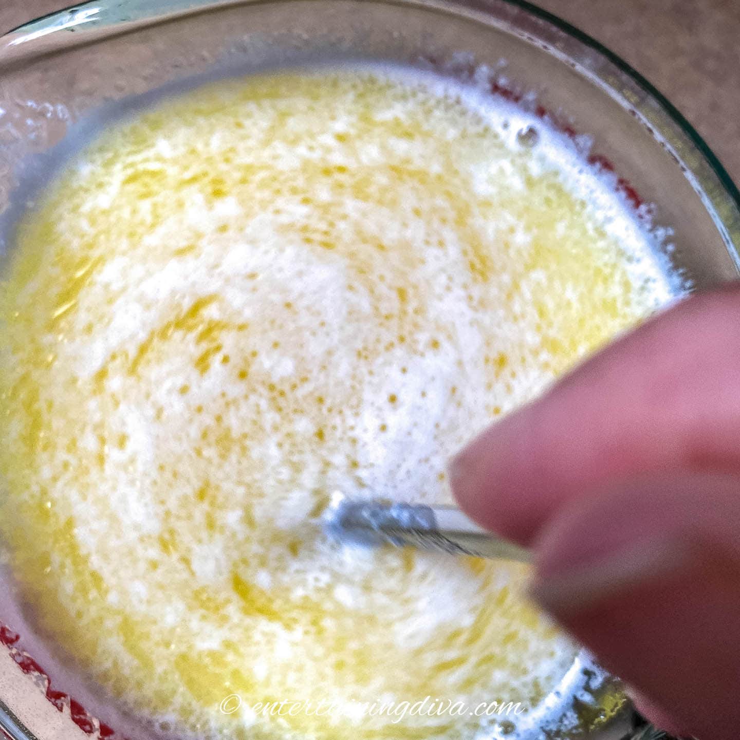 Milk, melted butter and sugar being mixed in a bowl