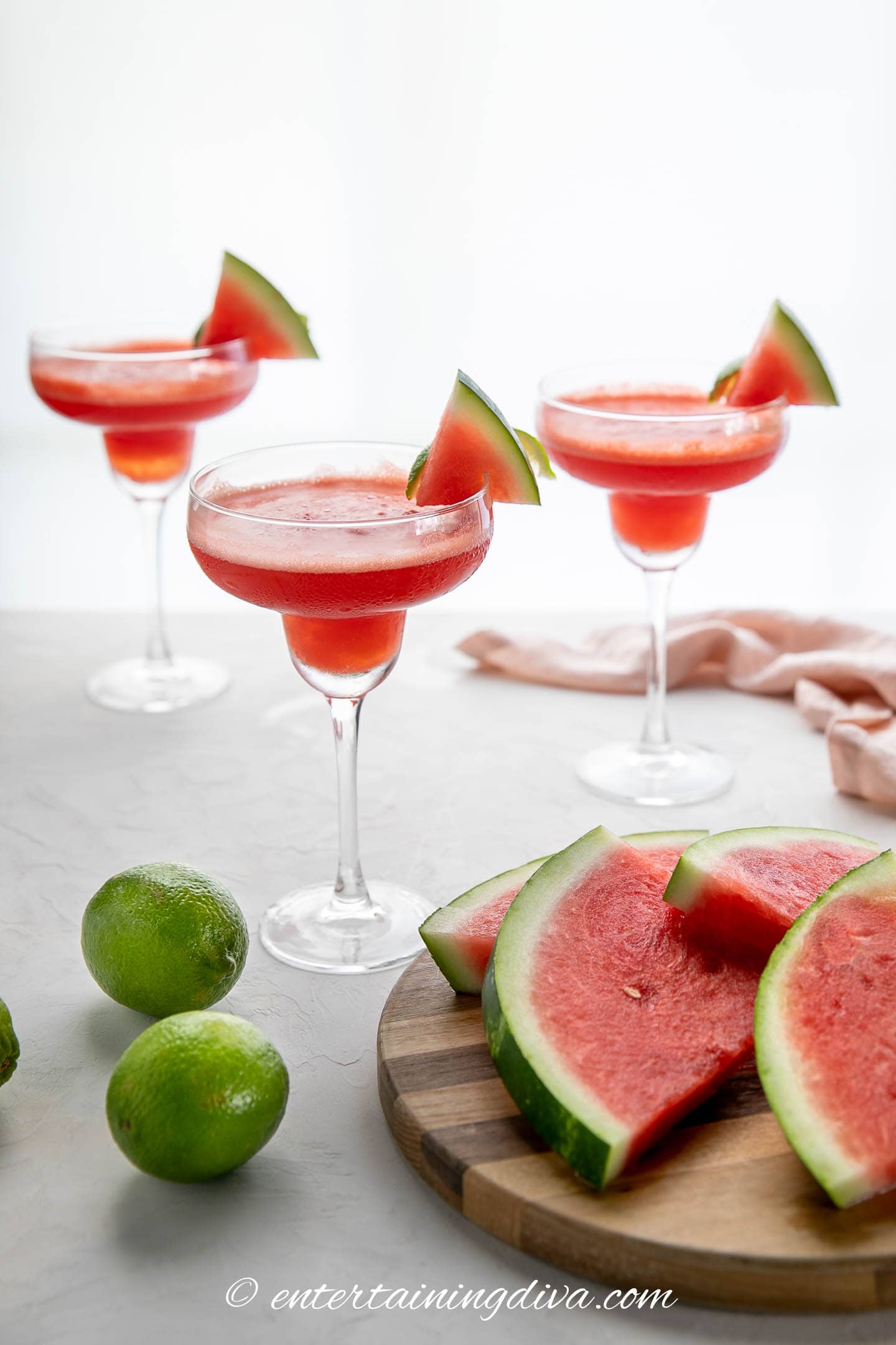 Frozen watermelon margaritas in 3 glasses garnished with slices of watermelon and limes