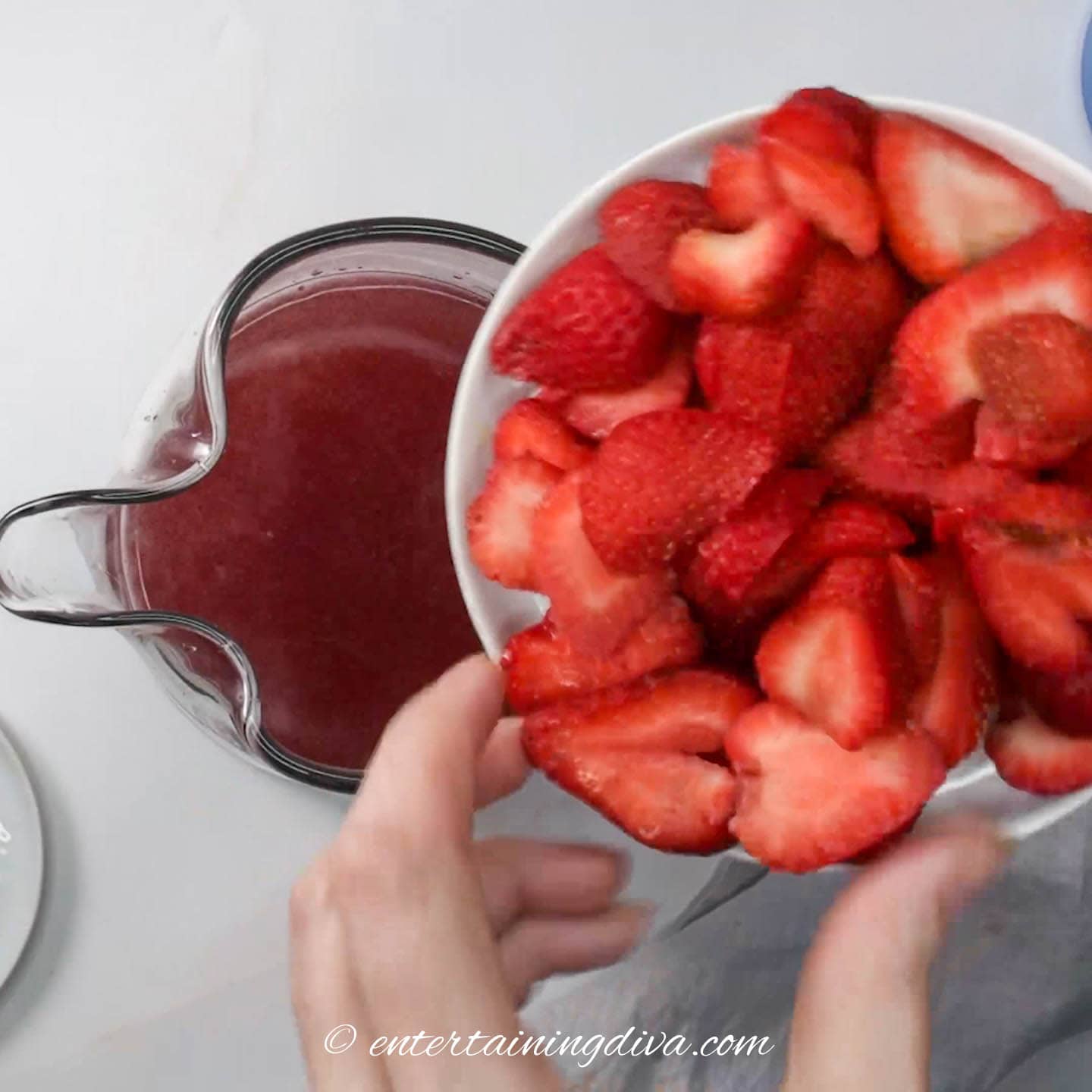 Plate of strawberries above a pitcher with wine and vodka mixture