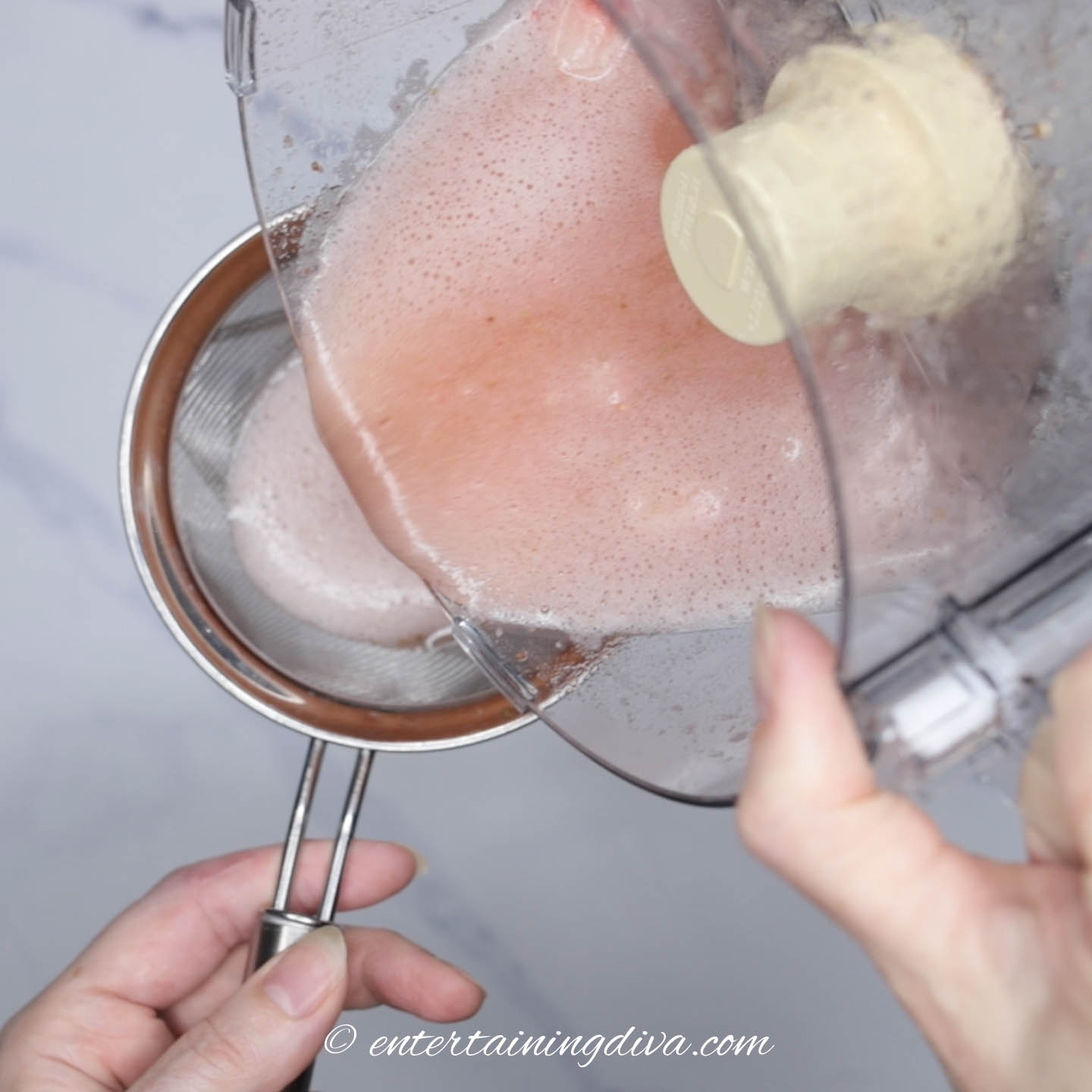 Strawberry and sparkling wine mixture being poured into a sieve