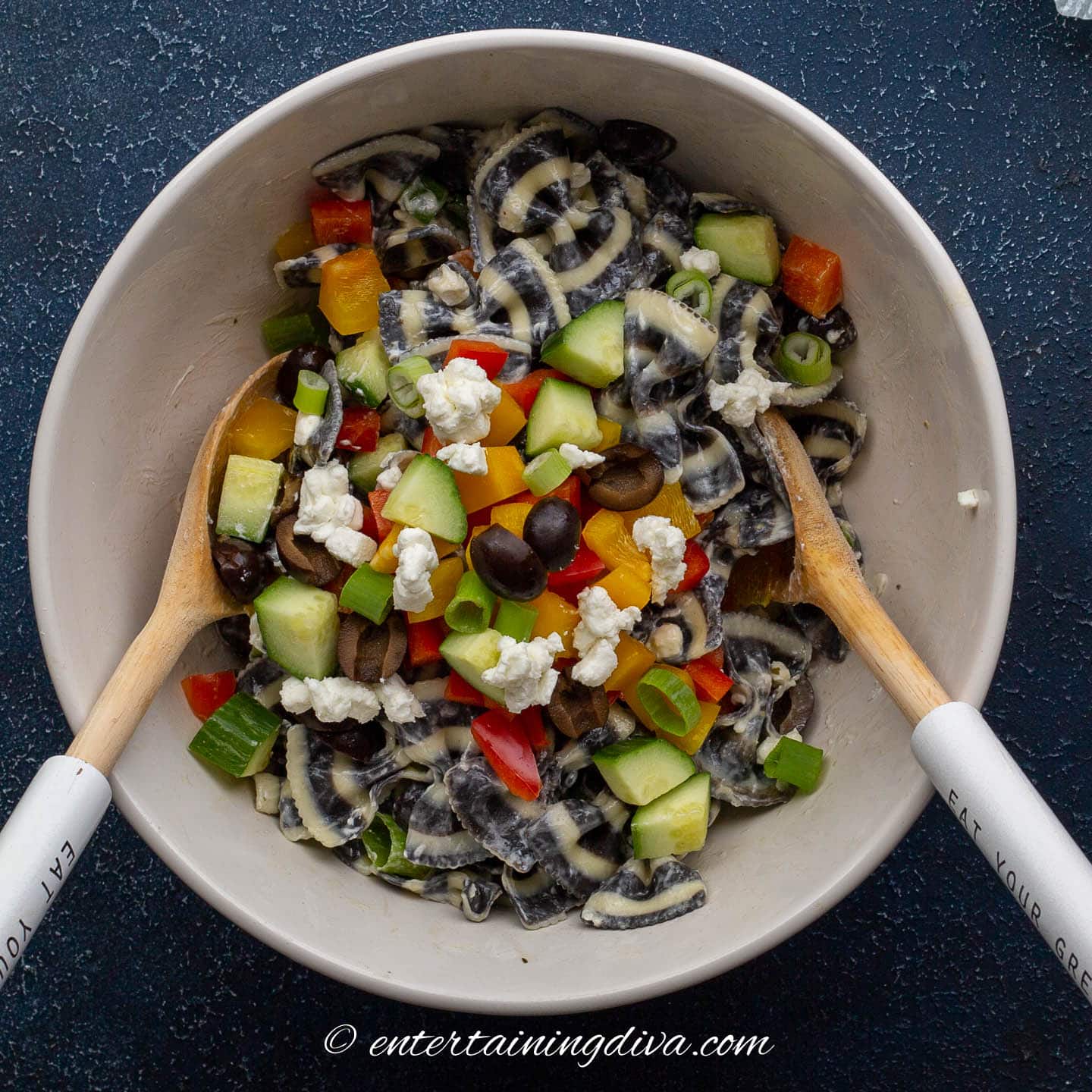 Zebra bow tie pasta with vegetables, black olives and goat cheese tossed in a bowl
