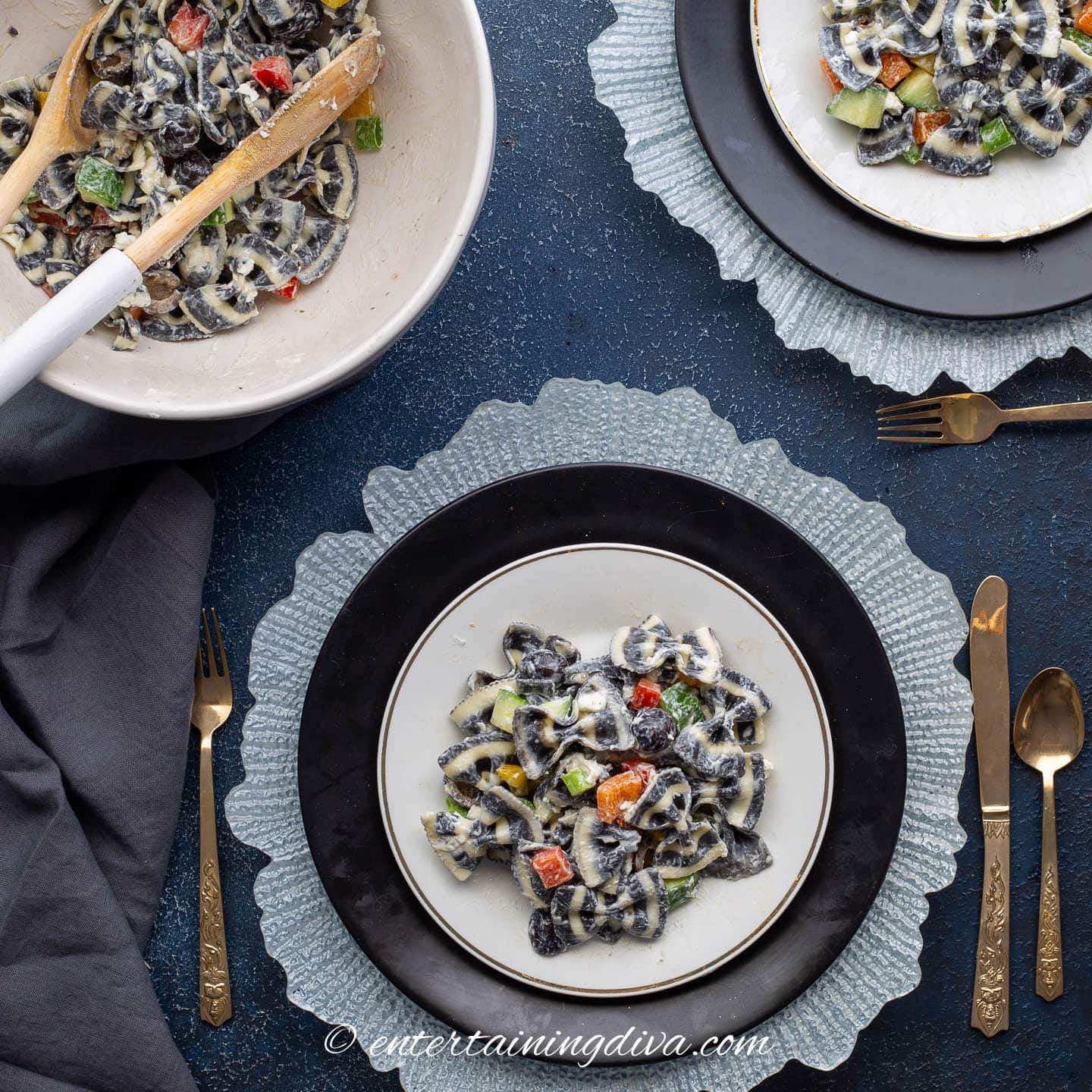 A bowl and two plates with black and white bow tie pasta salad 