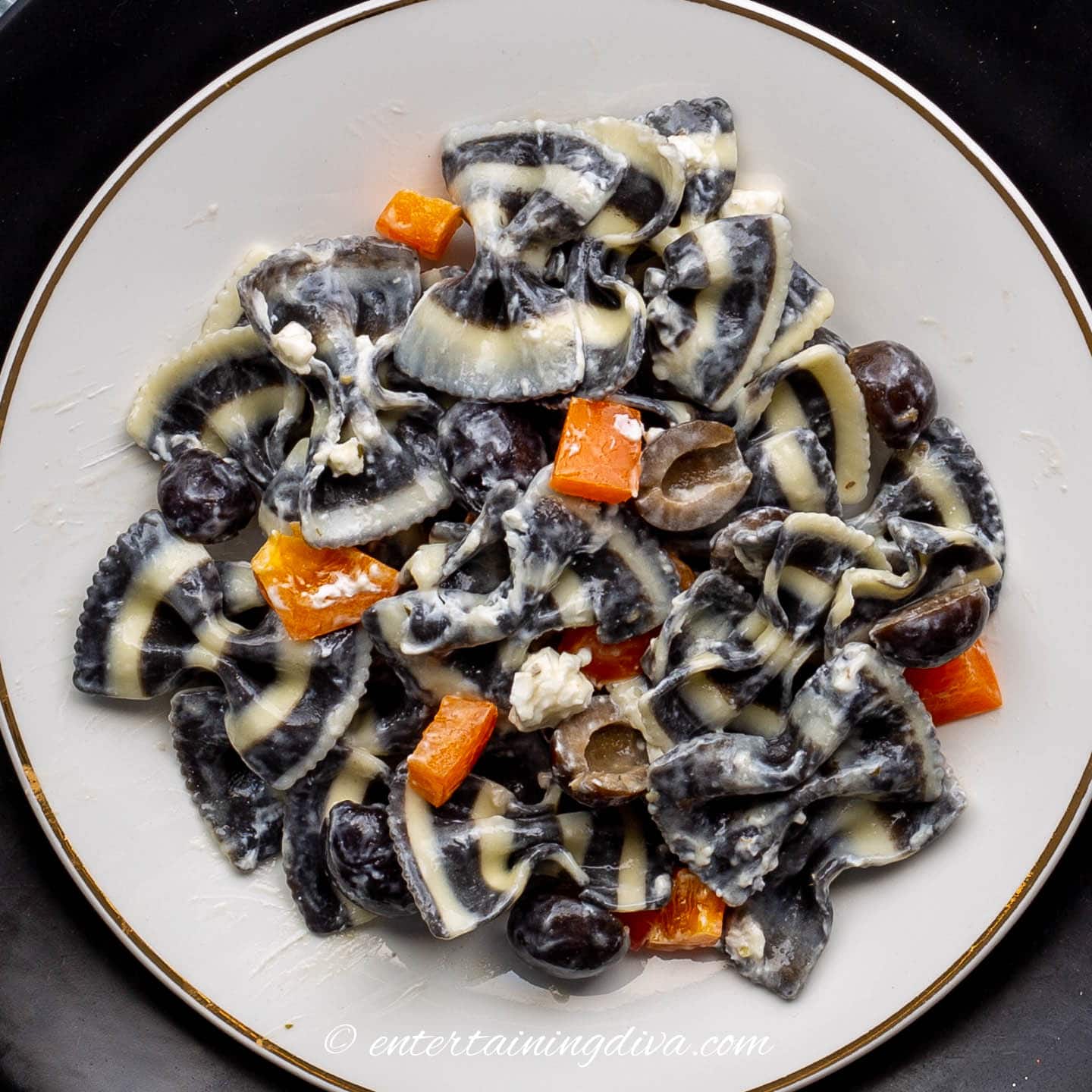 Black and white bow tie pasta with black olives, goat cheese and orange peppers