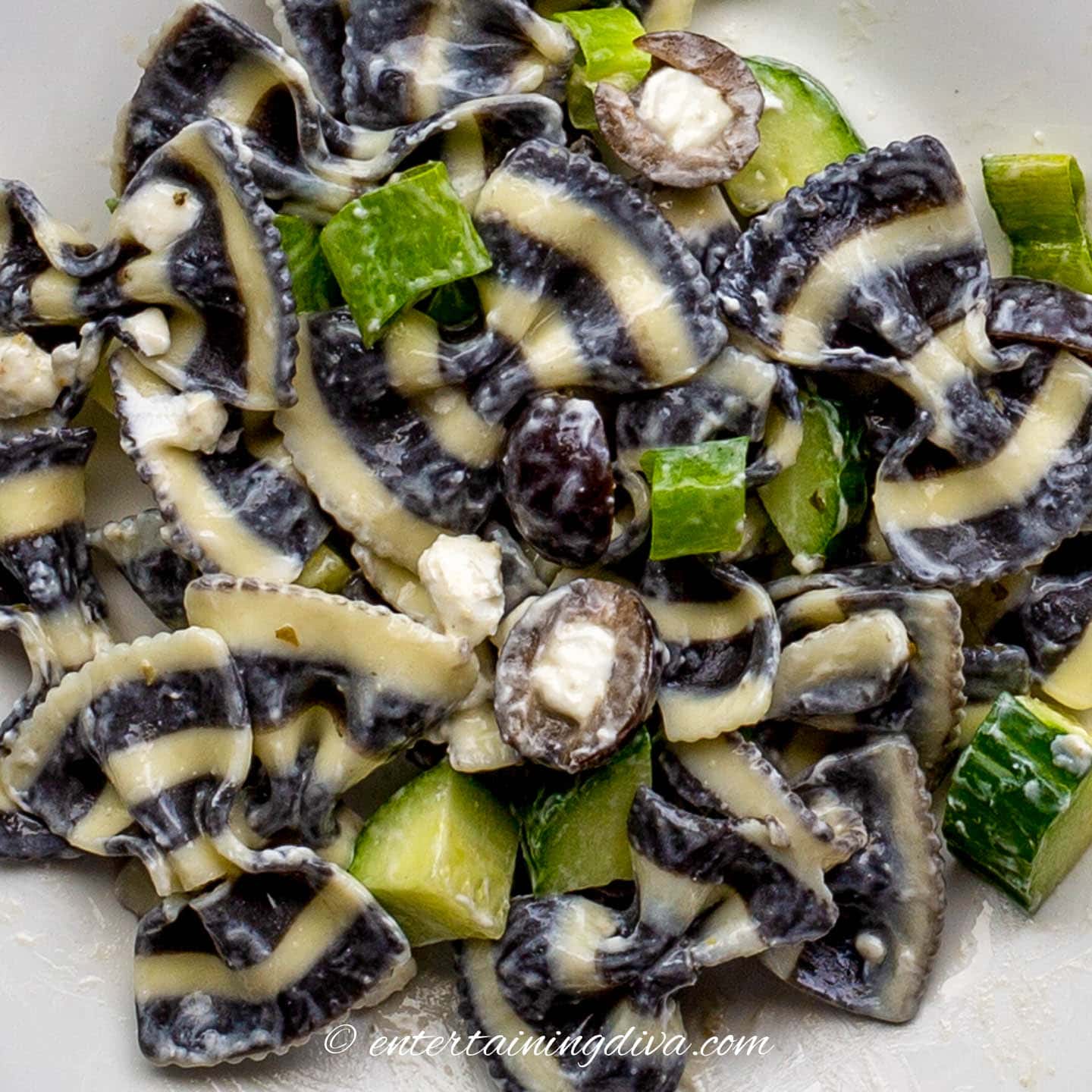 black and white bow tie pasta with black olives, goat cheese, green onions, cucumbers and Italian dressing