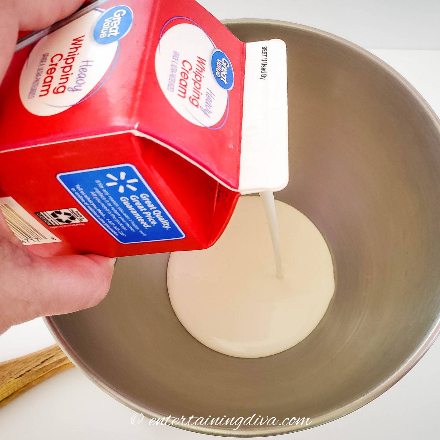 heavy cream being poured into a mixing bowl