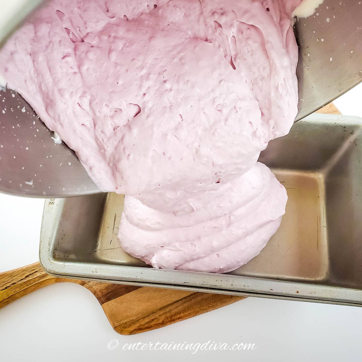 no churn raspberry ice cream being poured into a bread pan