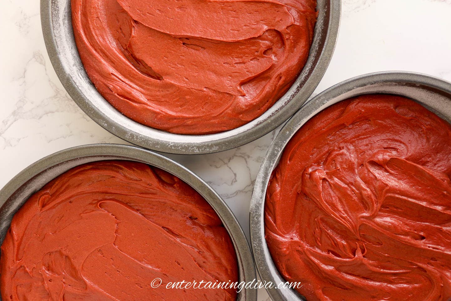 Red velvet cake batter in 3 cake tins