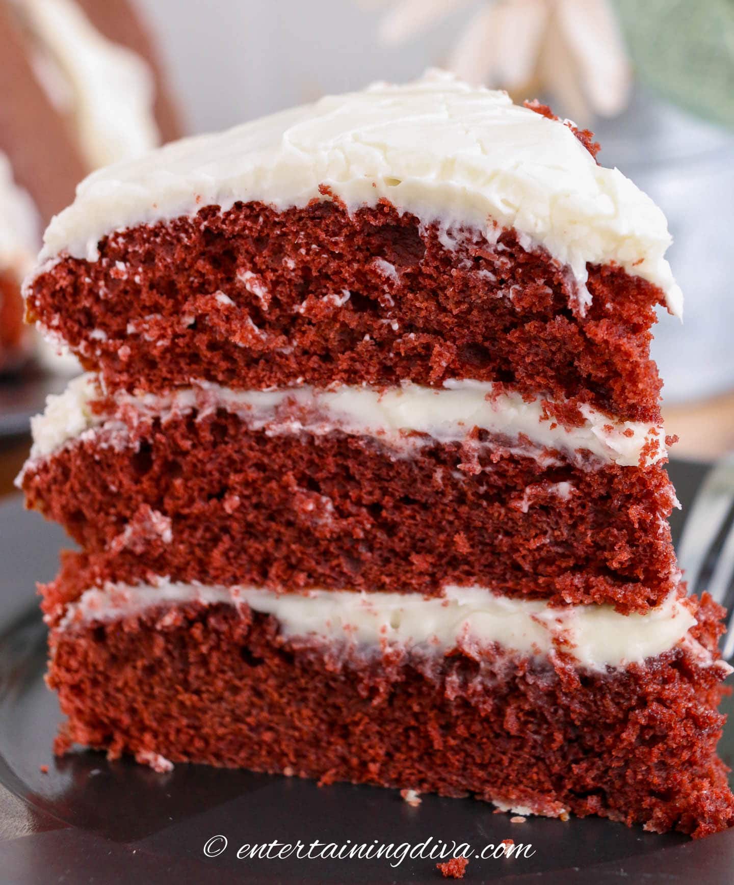 a piece of red velvet cake with 3 layers of icing