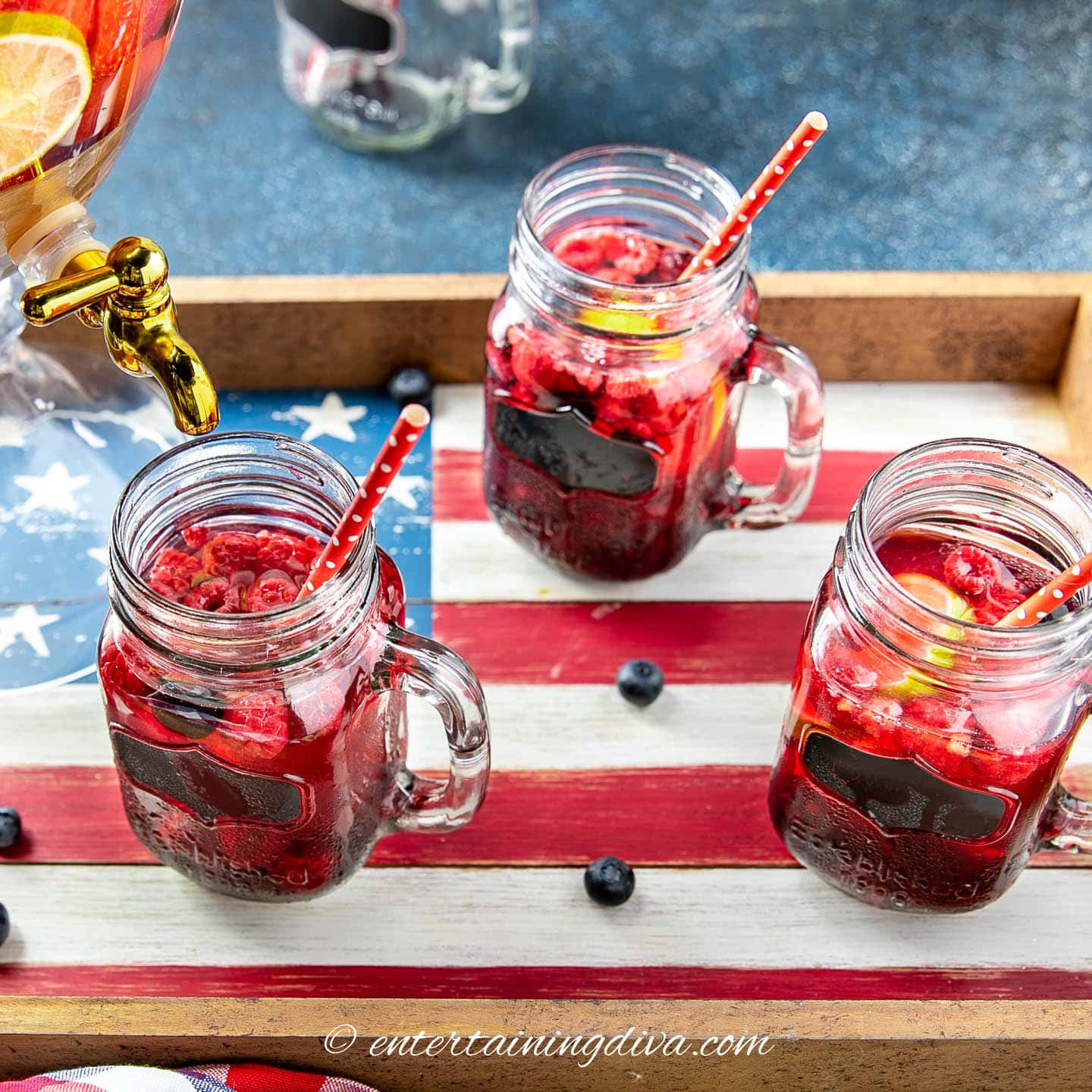 3 glasses of berries and lime sangria in mason jar cups on an American flag tray