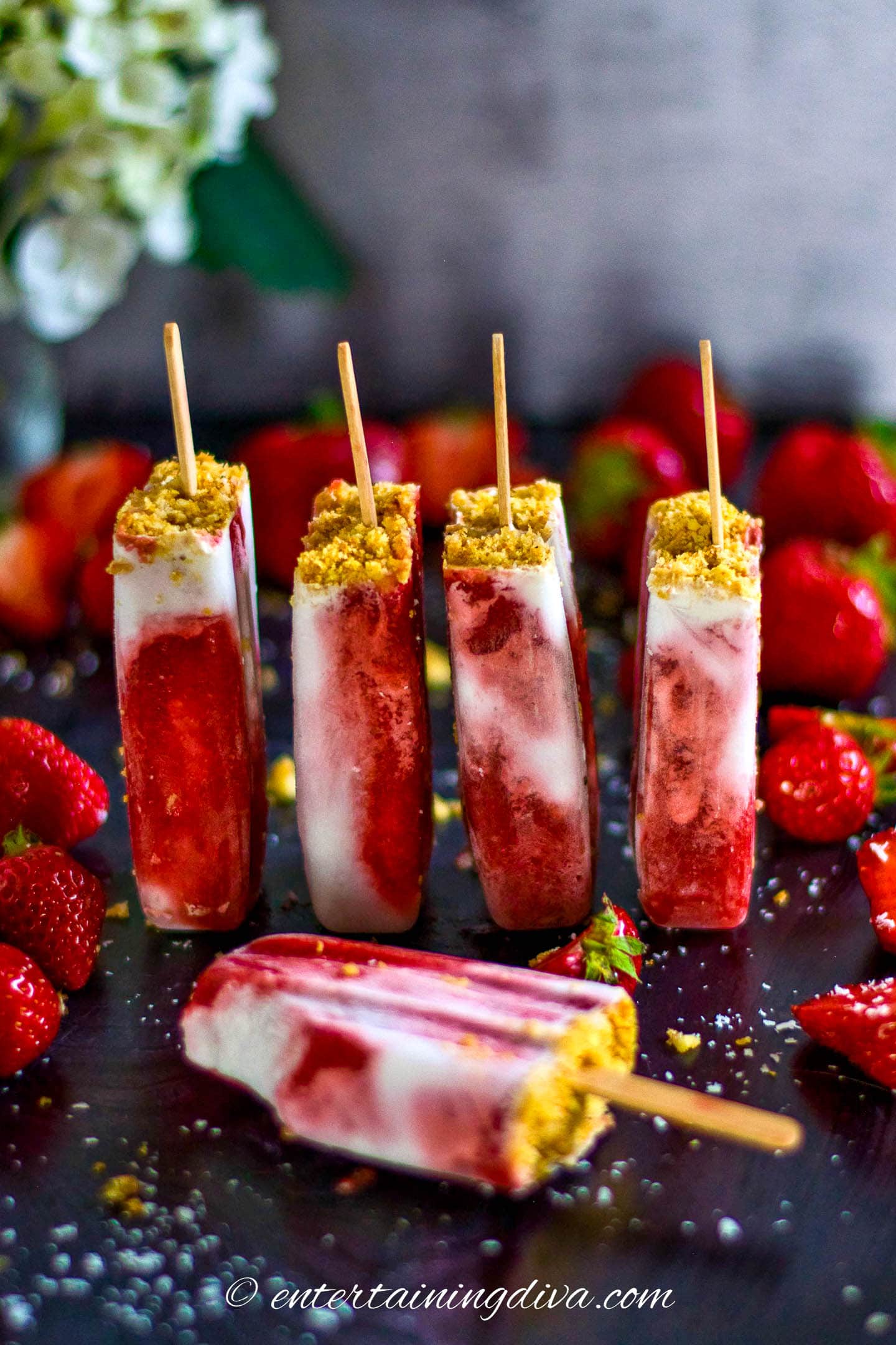 4 coconut milk and strawberry popsicles on end with one lying down in front