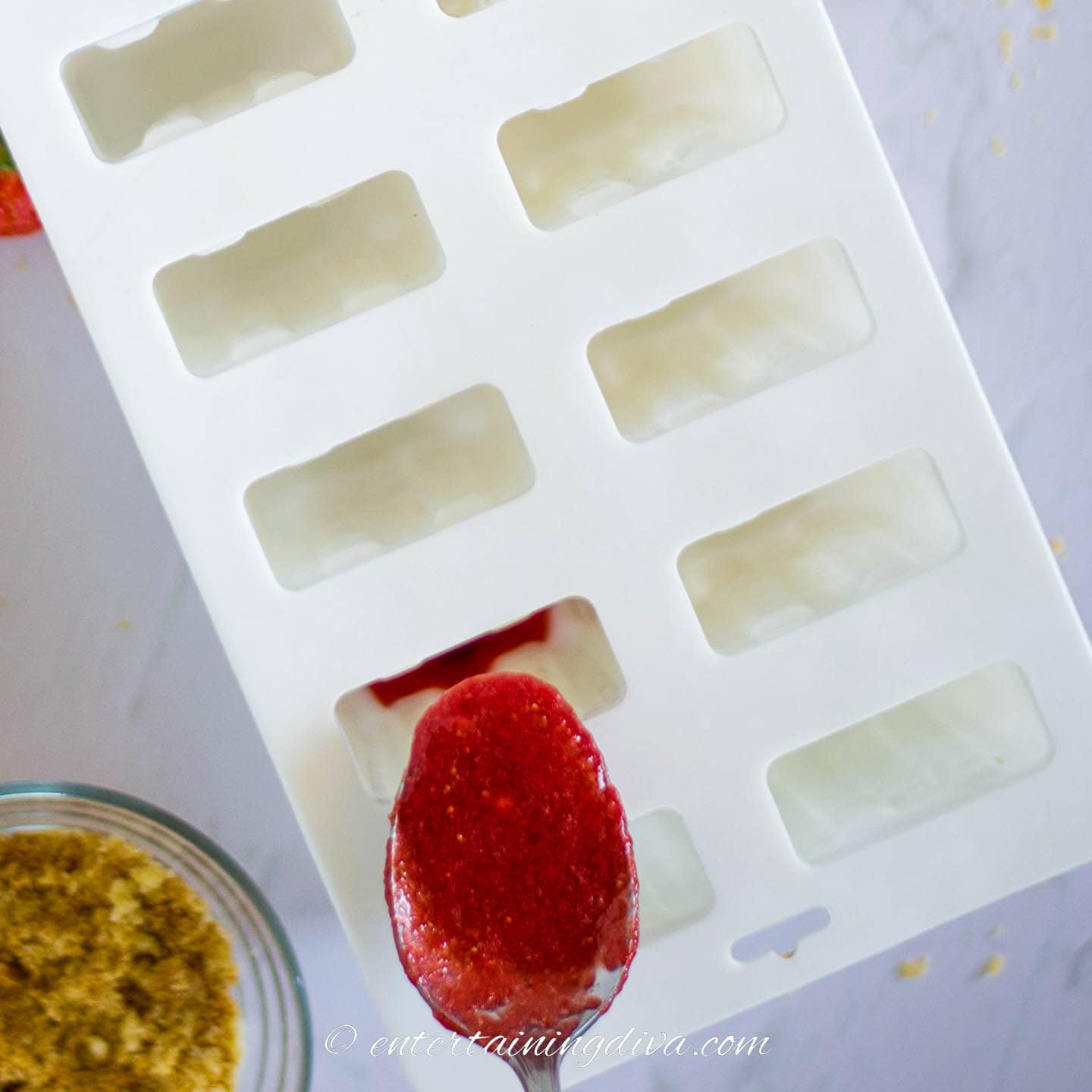 strawberry puree being added to popsicle mold
