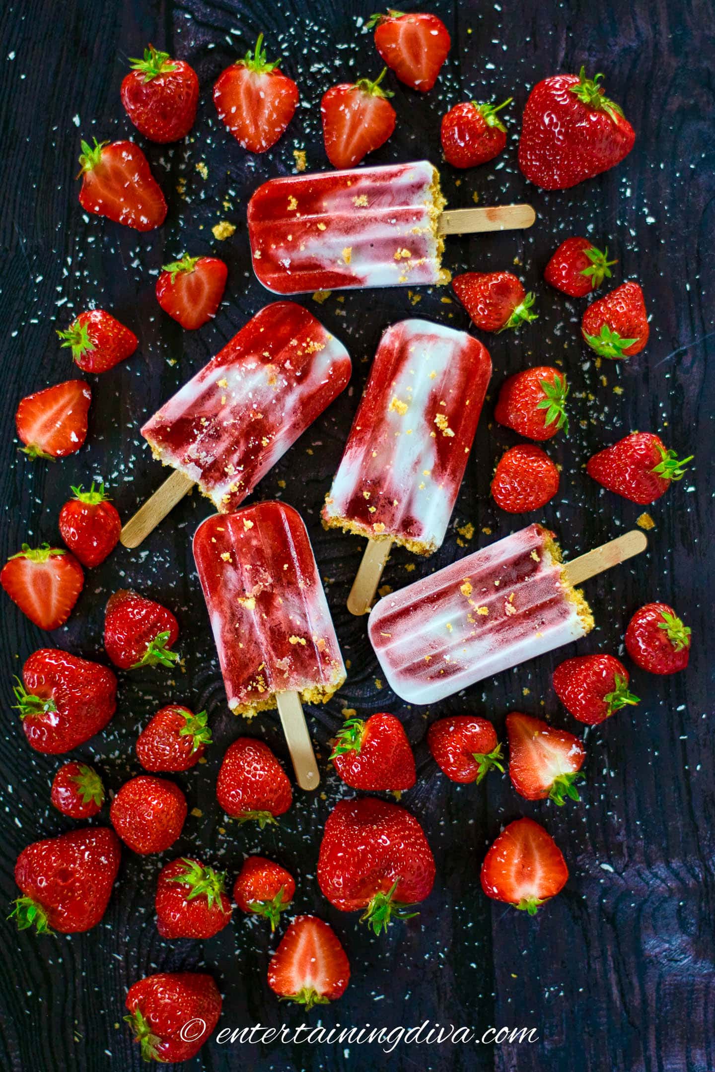 coconut milk and strawberry popsicles on a table surrounded by strawberries