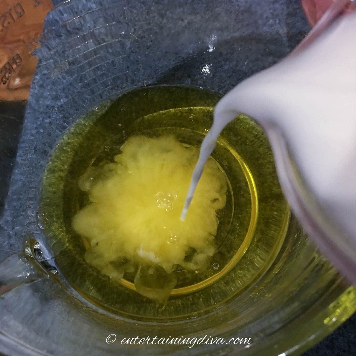 coconut milk and malibu rum being poured into pineapple jello mixture