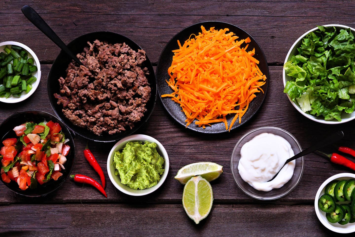 toppings for nachos - including green onions, pico de gallo, guacamole, grated cheese, sour cream, lettuce and jalapeno peppers