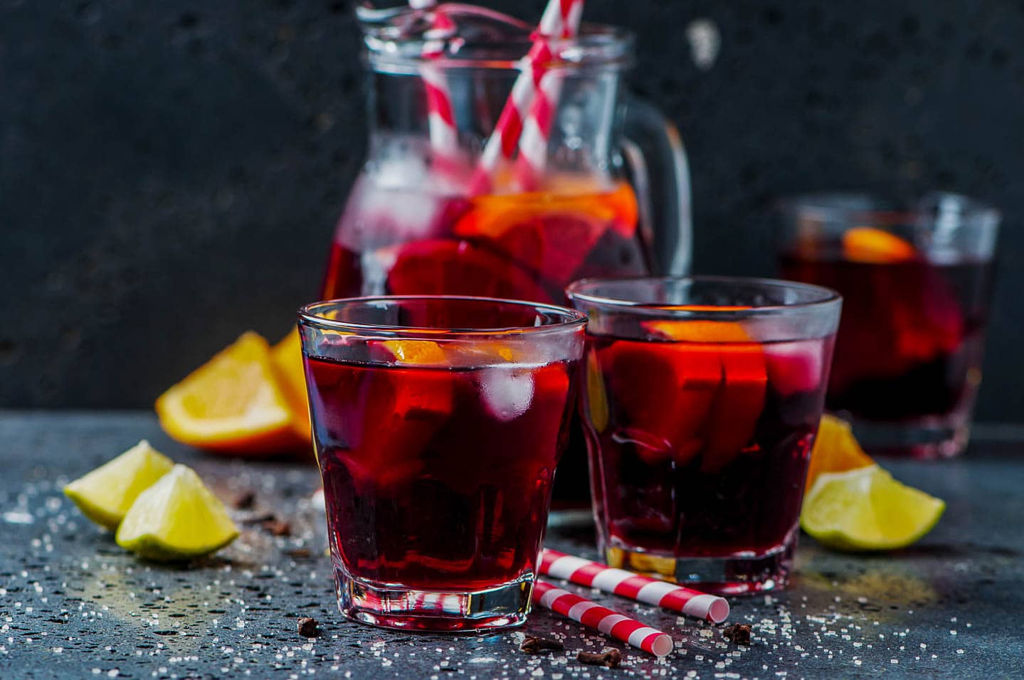 two glasses of red wine sangria with a pitcher in the background