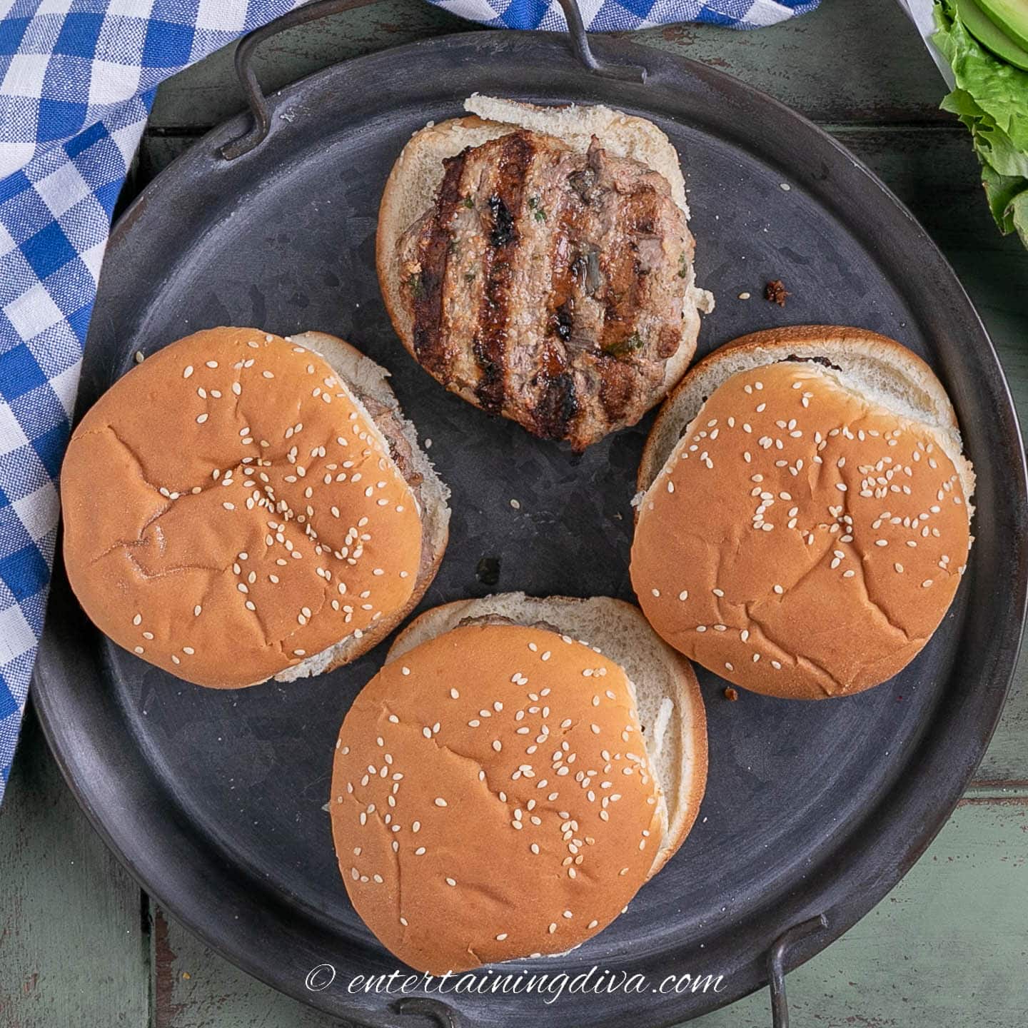 4 pesto turkey burgers on a tray, 3 with buns on top and 1 without
