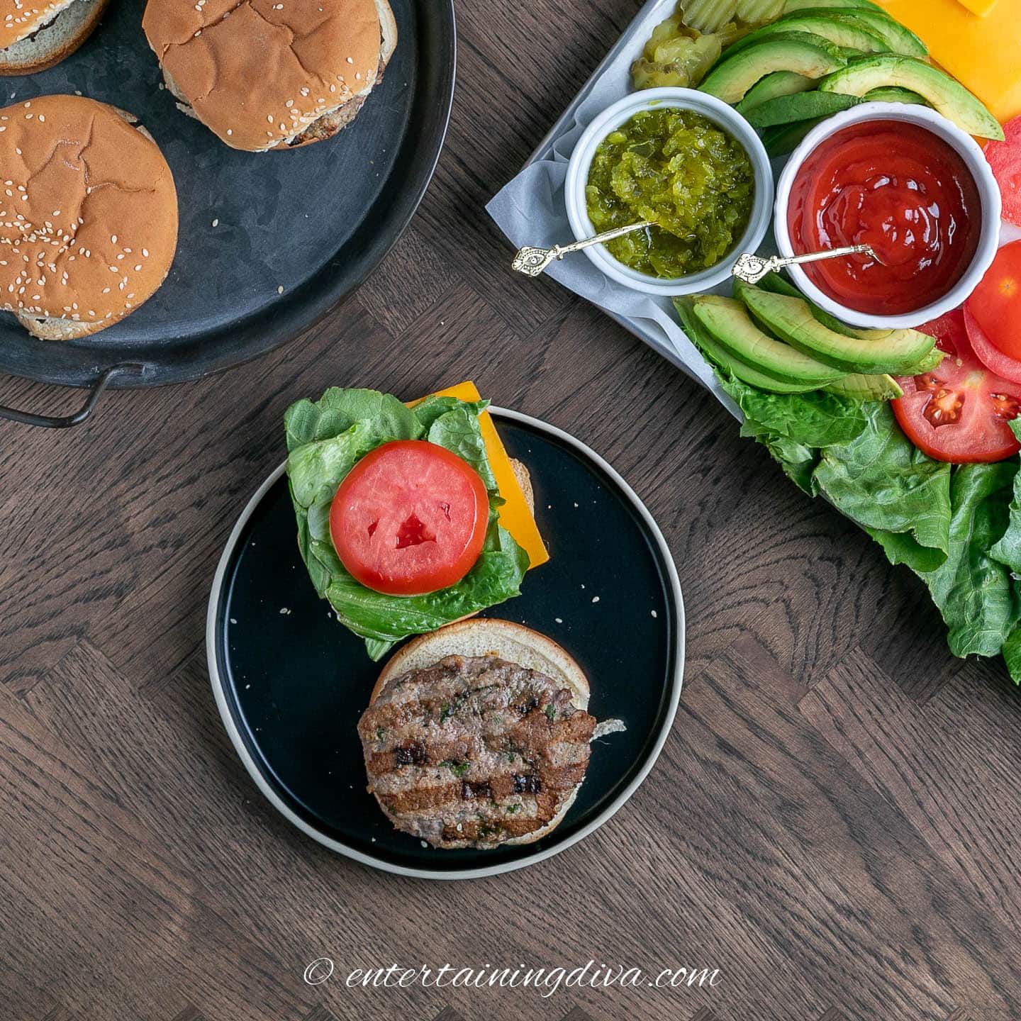 open faced lemon cilantro turkey burger on a plate beside a platter with condiments and other burger fixings