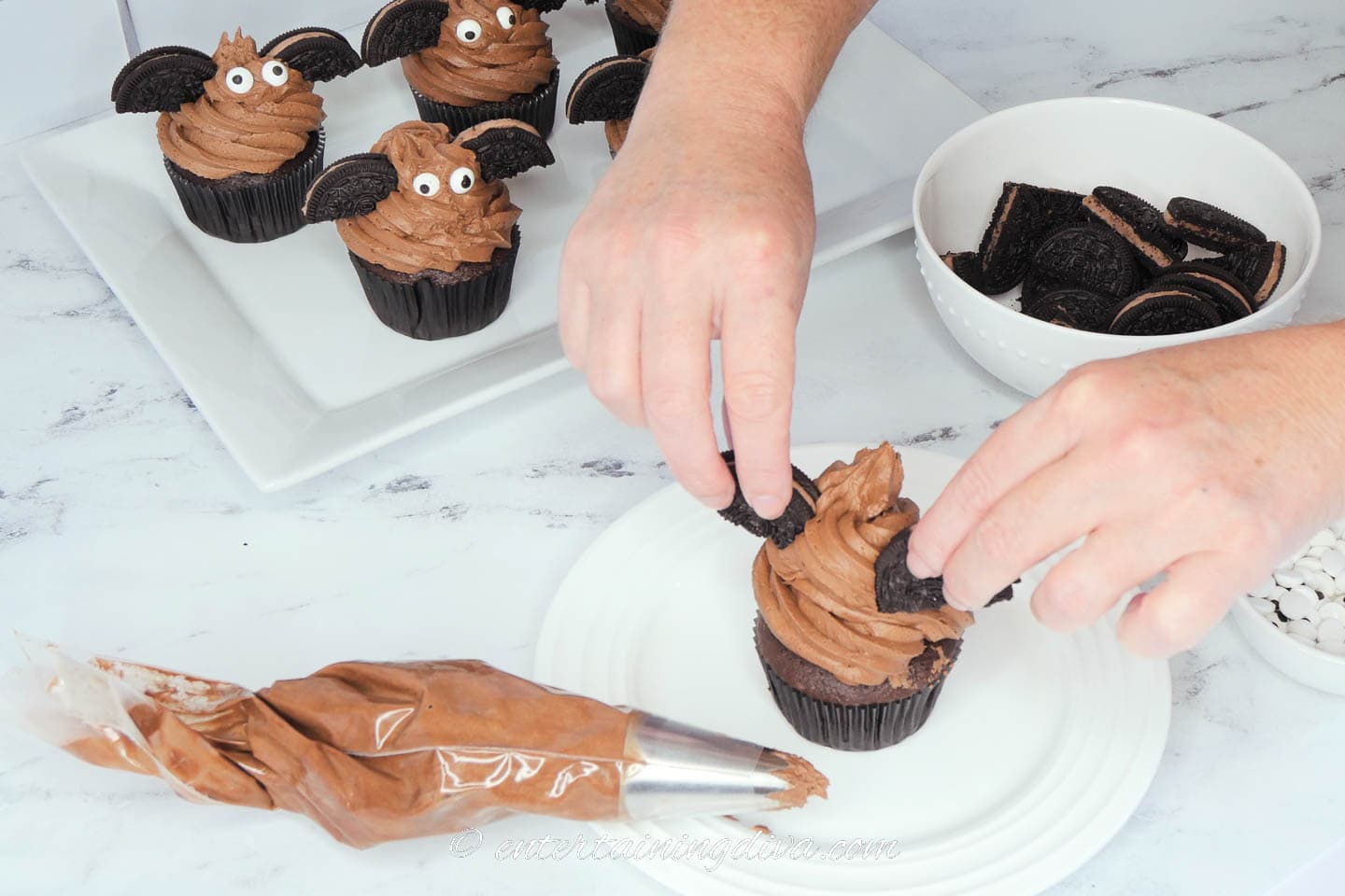 Sticking the oreo cookies into the chocolate frosting on the cupcake