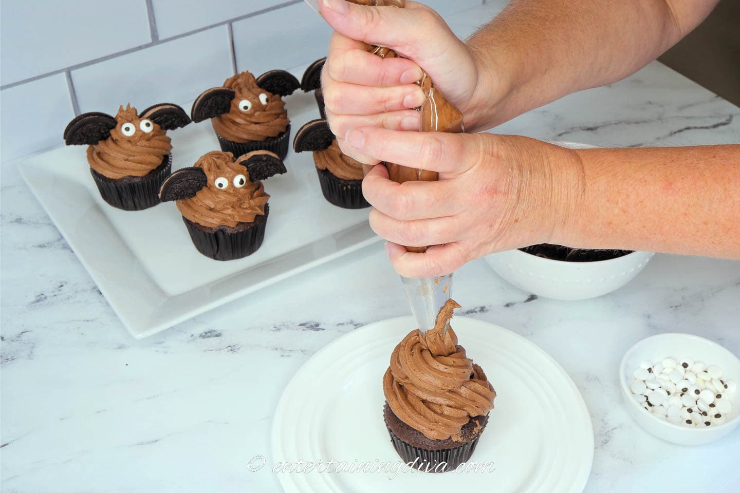 Piping the chocolate frosting onto the chocolate cupcake
