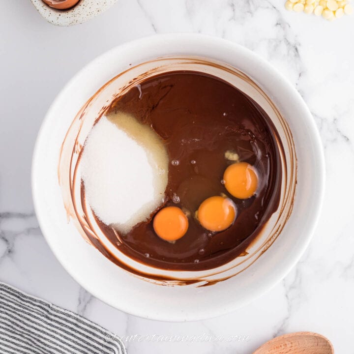 eggs and sugar with melted chocolate in a bowl