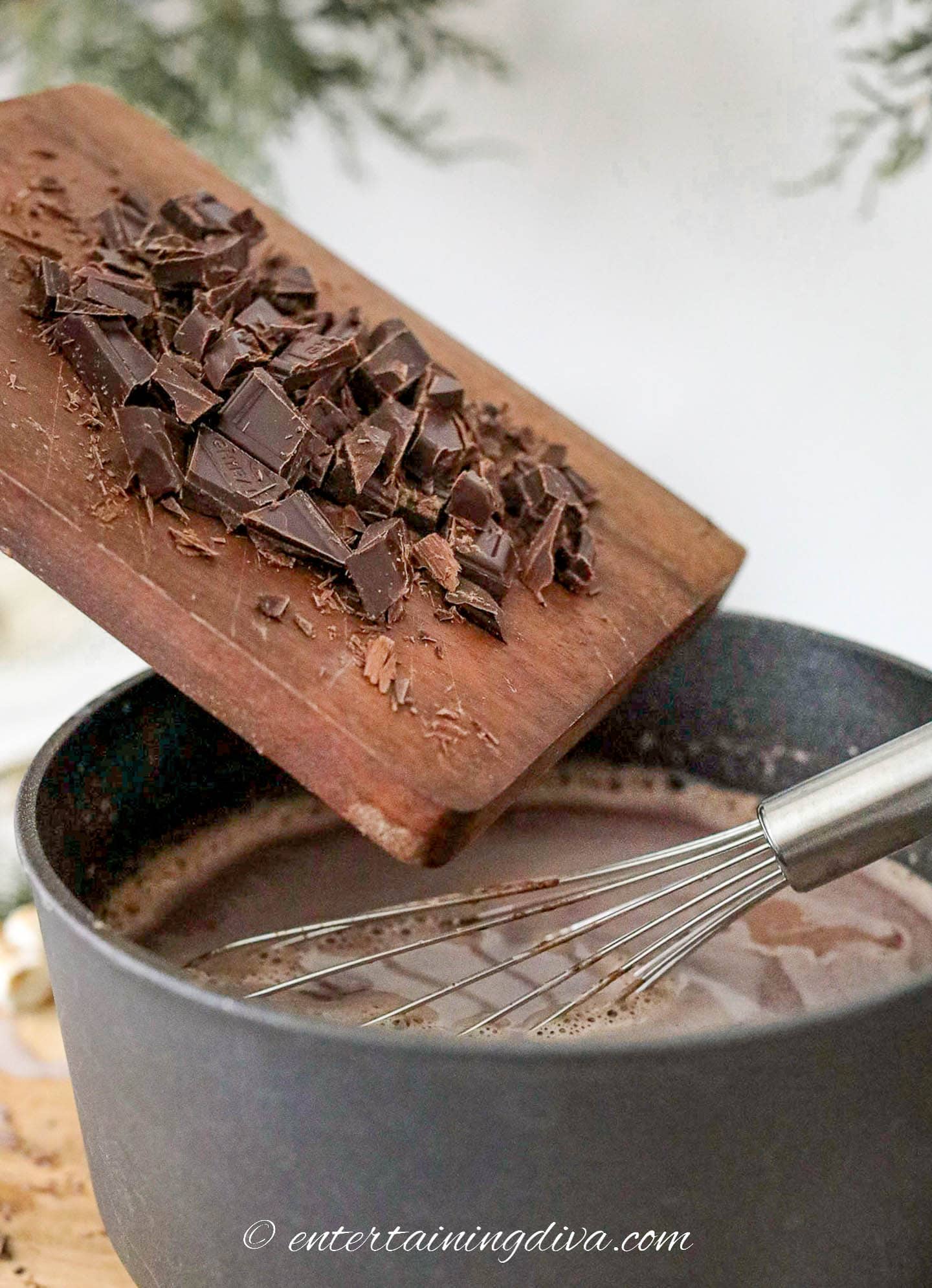 Chopped chocolate being poured into a pot of hot cocoa