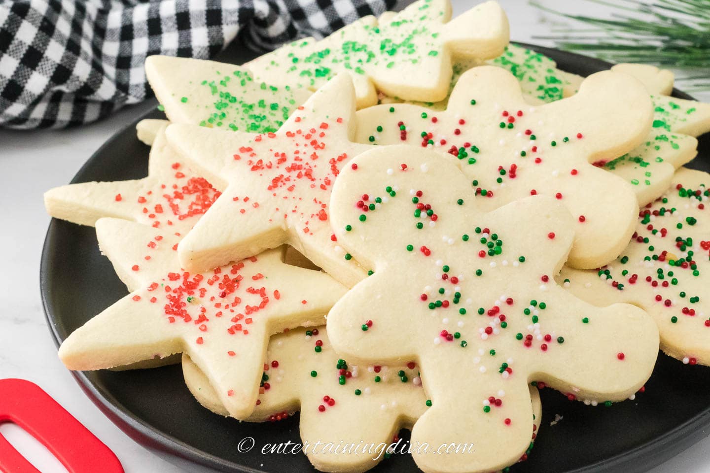 A pile of shortbread cut out Christmas cookies with sprinkles