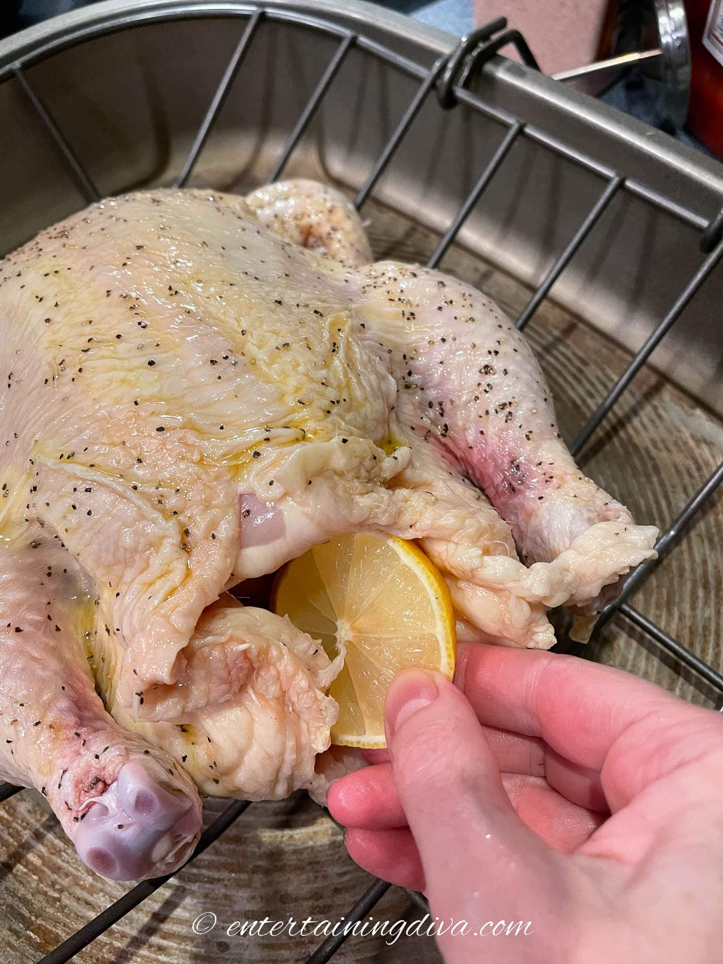 Turkey being stuffed with lemons and thyme