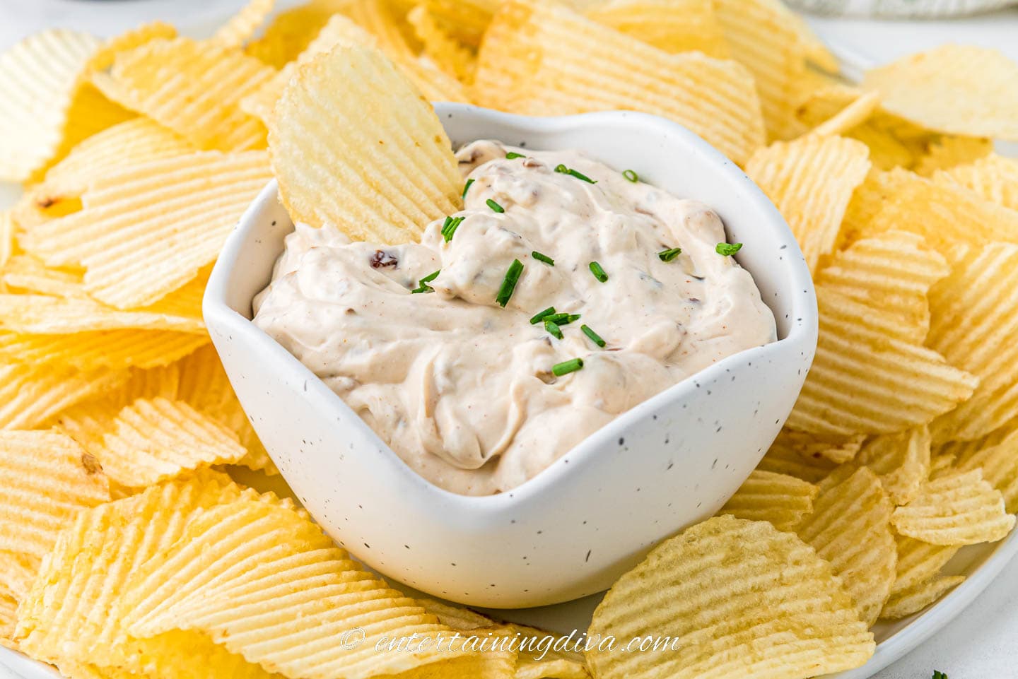 Bowl of caramelized onion dip on a plate with chips