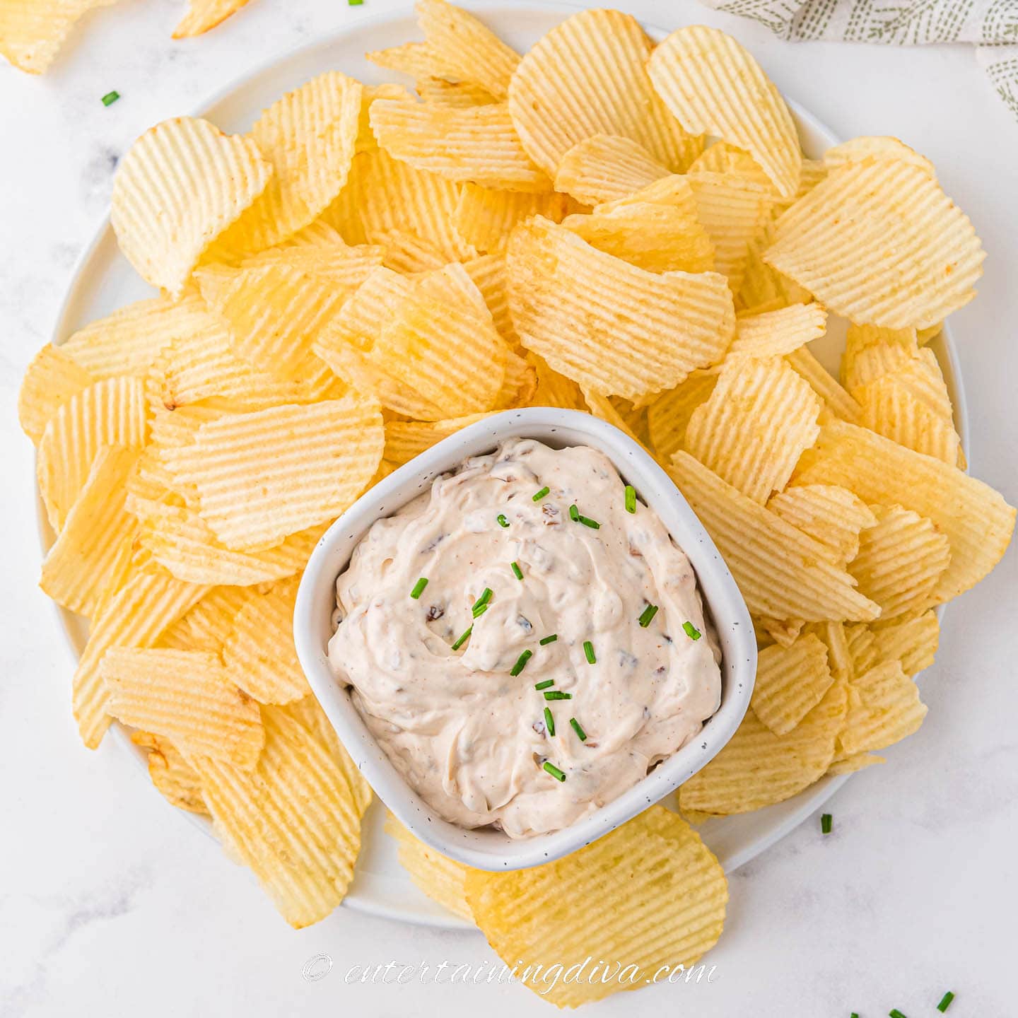 An overhead picture of a plate of chips with a bowl of caramelized onion dip in the middle