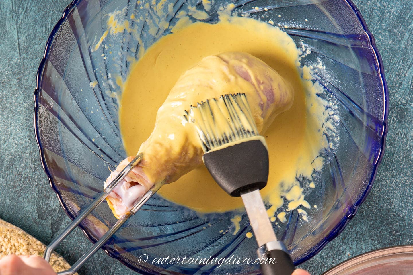 chicken leg being brushed with dijon mustard and lemon juice